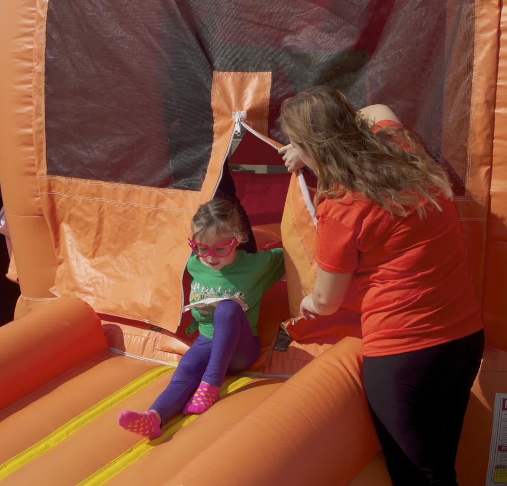 Key Club President Addie Carlson helps a girl out of the pumpkin-shaped bounce house. Carlson led a group of Key Club volunteers at the Austin State Supported Living Center's annual Spooktacular fall festival Sunday.