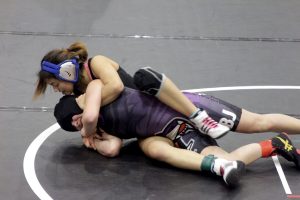 McCallum wrestling team captain, Adriana Boortz, leads by example for her fellow wrestlers as she keeps the upper-hand against LBJ's 102-pounder. Boortz eventually pinned her opponent during the second round en route to defending her district title. Photo by Beth Bishop
