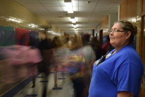 LEFT: Officer Georgia Gonzalez watches as students pass through the main hallway during passing period. “I really like interacting with the students as they go to class.” Gonzalez said. Photo by Gregory James. 