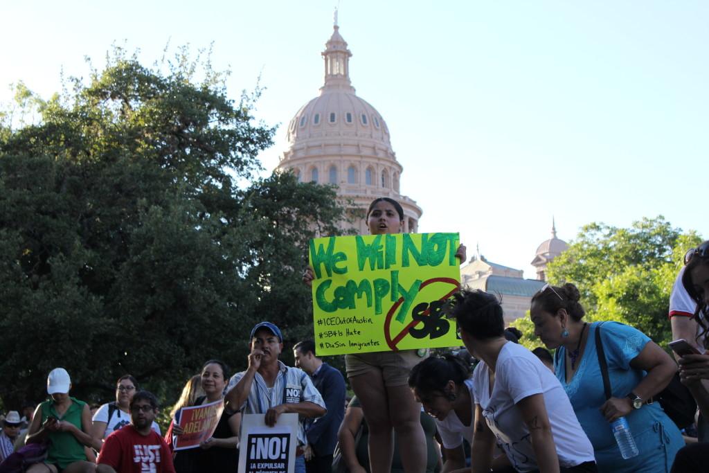 A child protests SB4 during the International Worker’s Day protest outside Gov. Abbott’s office. Photo by Diego Guttierrez.