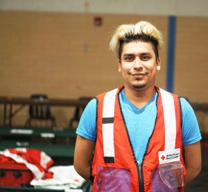 Rafael Corrales stands in the small gym with the many cots and gear from all the Red Cross volunteers sheltered there.